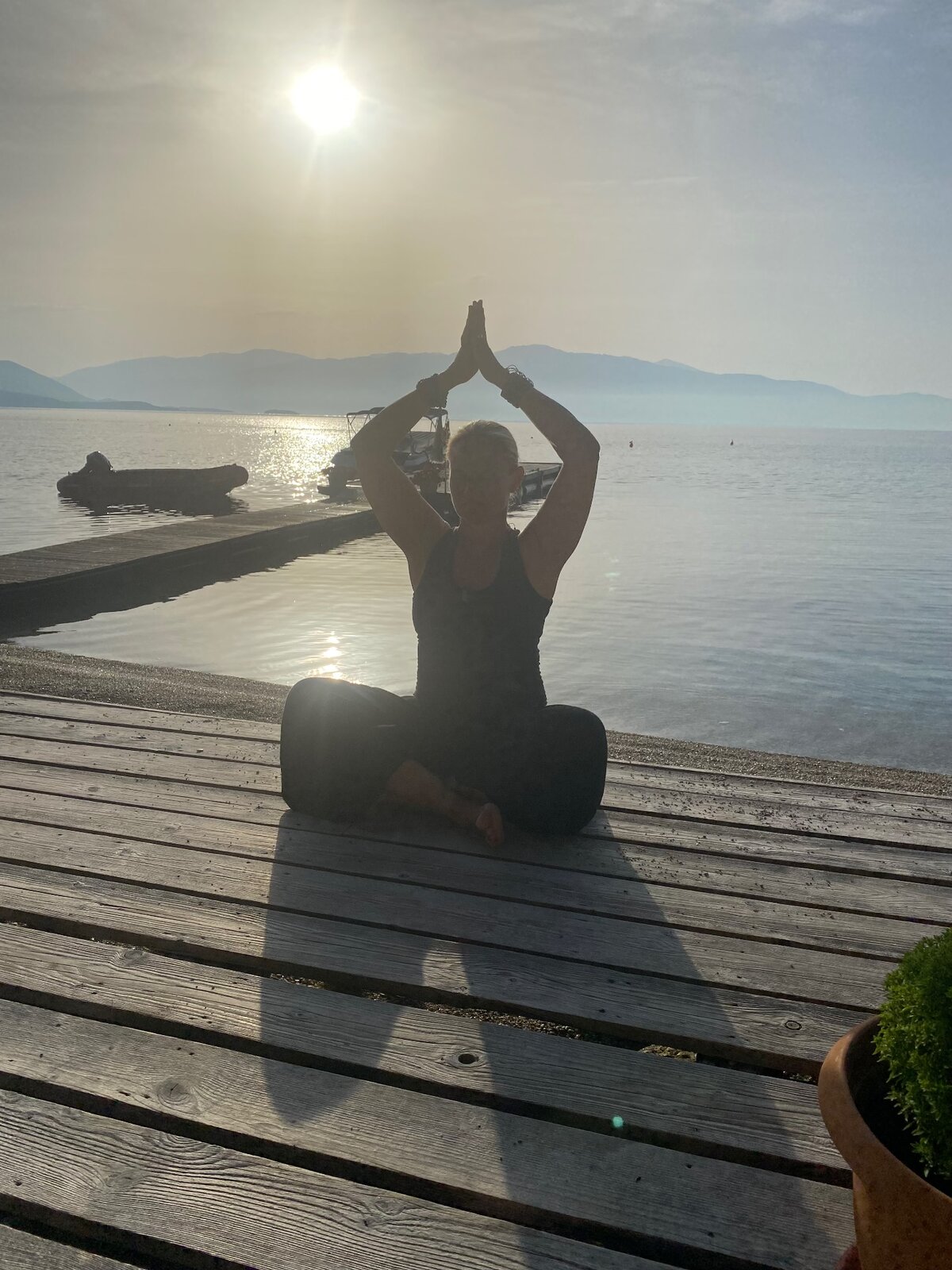 Elisabeth i yogapositur på en brygge ved sjøen i solnedgang
